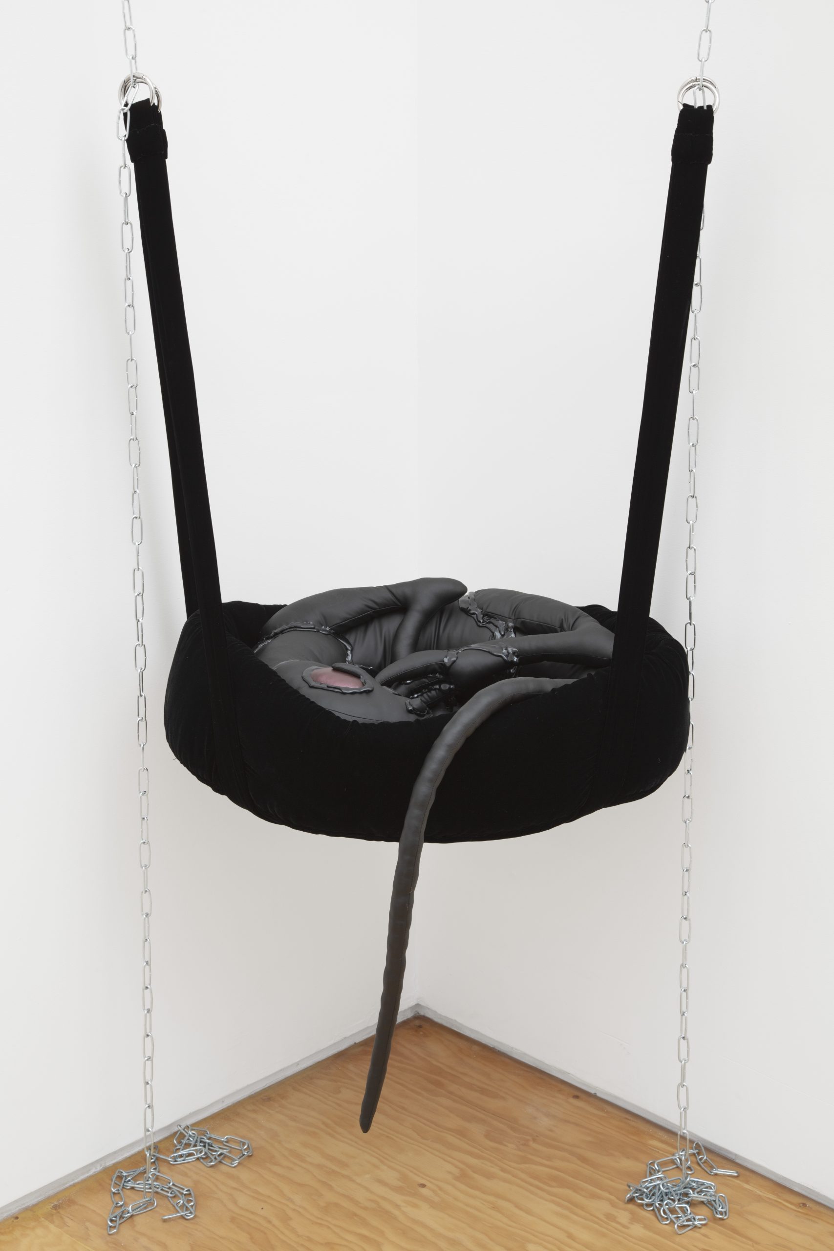 sculpture of fabric baby dragon cradle hanging by chain