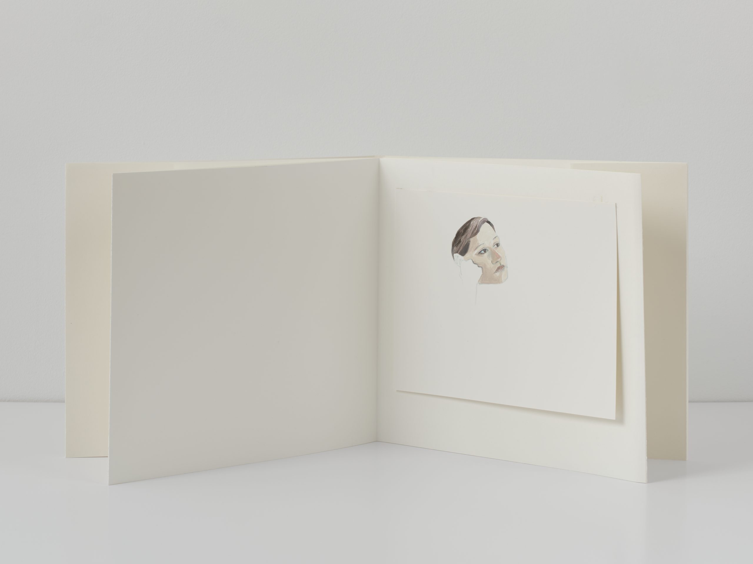 White/blank open book with mounted portrait outline with painted face.