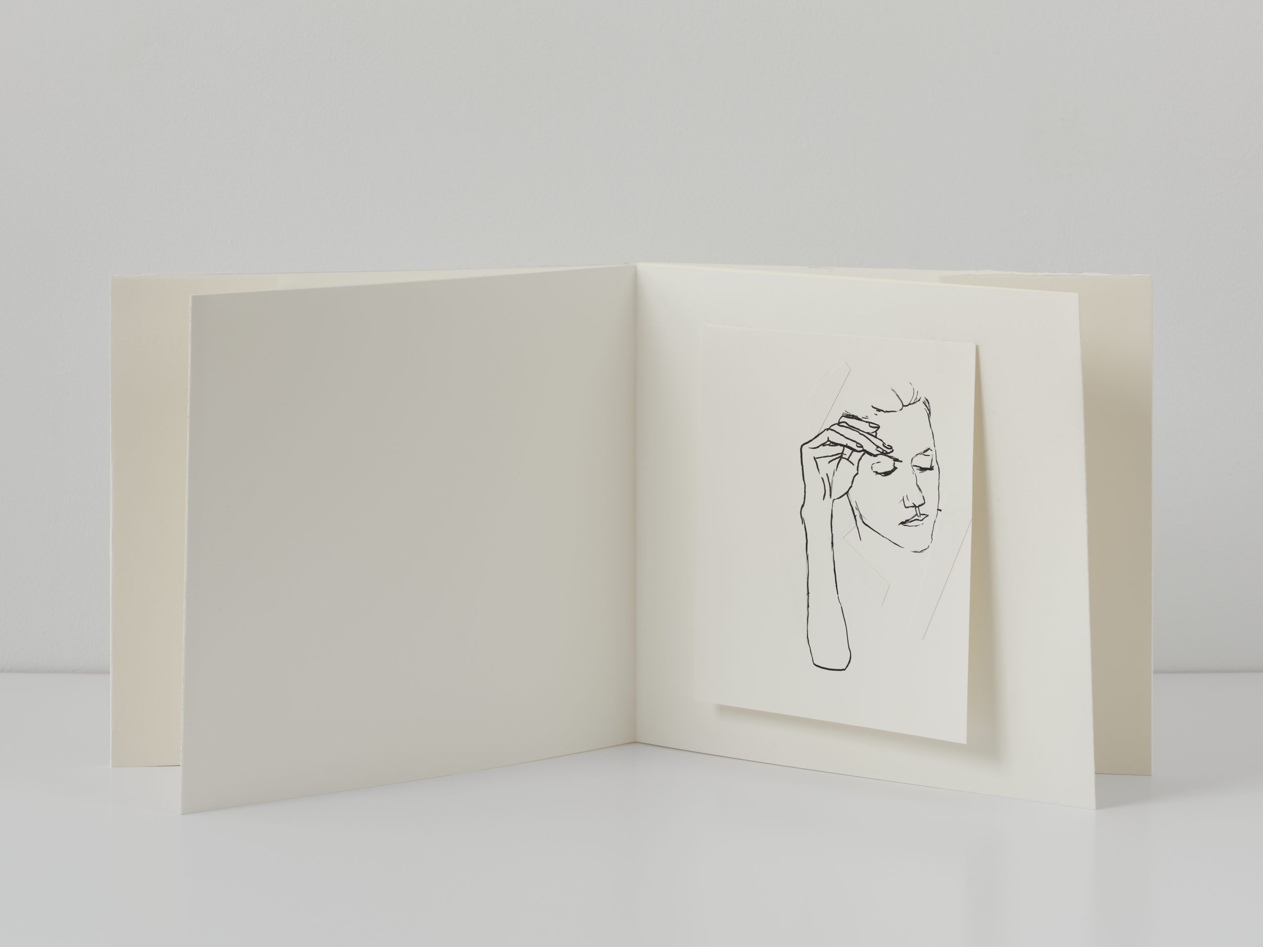White/blank open book with mounted portrait drawing in black ink.