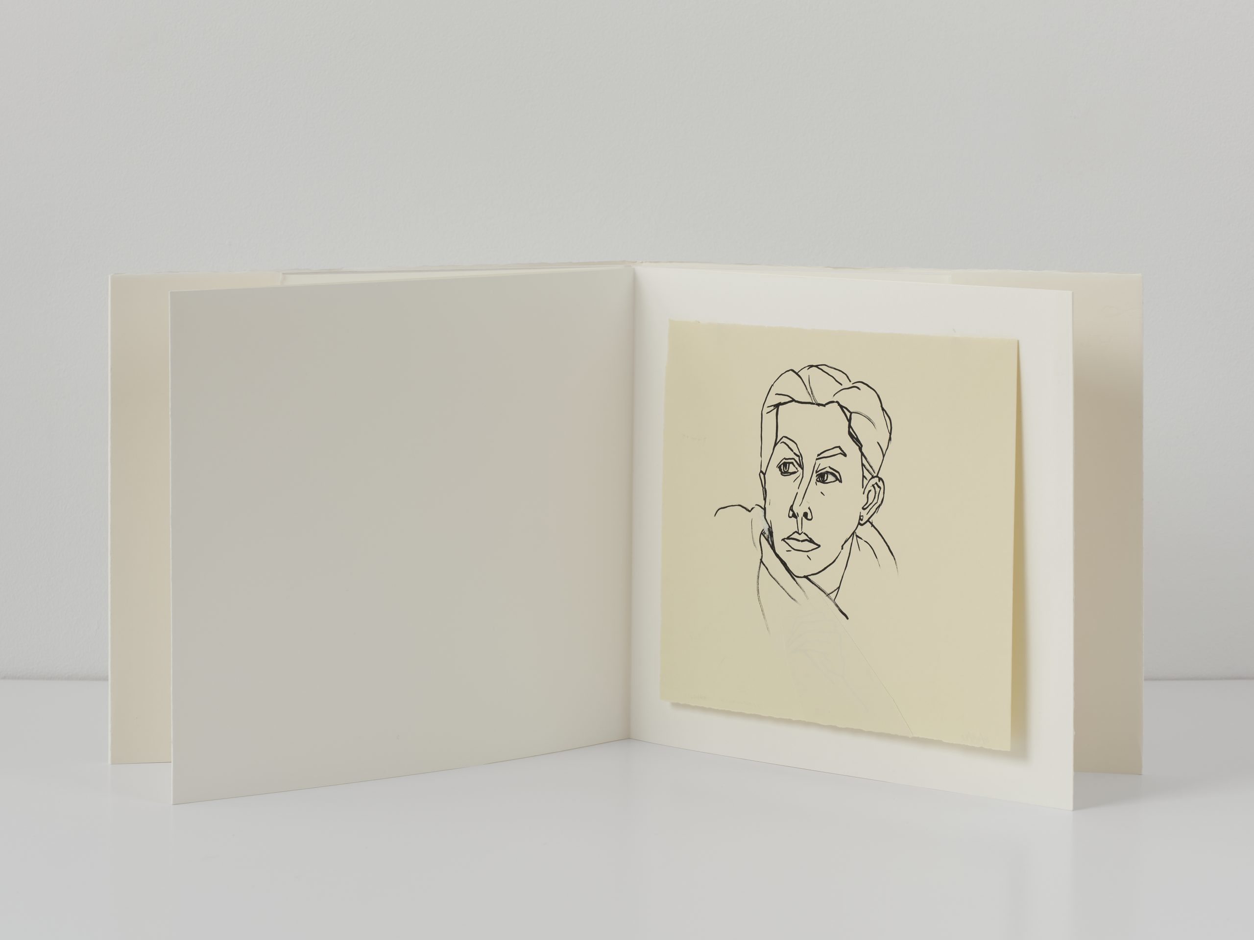 White/blank open book with mounted self portrait drawing in black ink.