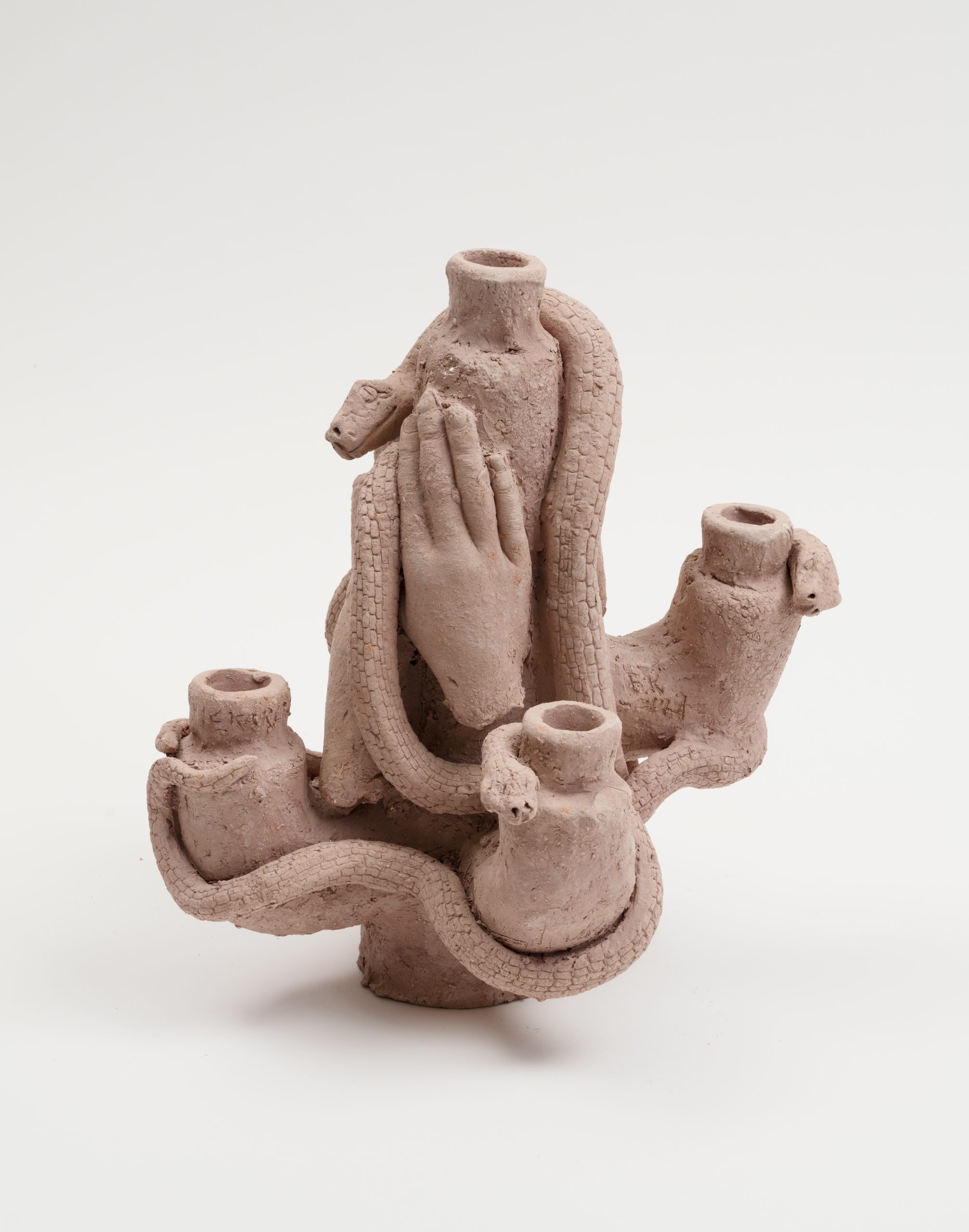 Ceramic candle holder by Edith Karlson. Snake climbing up scaley structure and hands holding onto it.