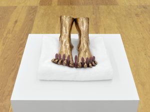Sculpture of feet in Cast bronze with porcelain and ceramic decals (on-glaze) nails by Man Yau. Displayed on white folded towel in a white pedestal.