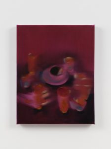 Blurred, magenta-toned still life of glowing cups encircling a dark, circular center.